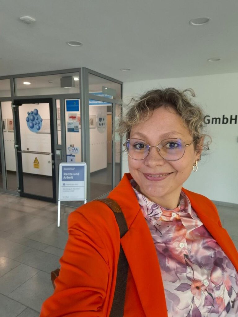 Referentin im Eingangsbereich der EAA Stelle Mittelfranken mit Werbeaufsteller zum Seminar Arbeit und Rente
